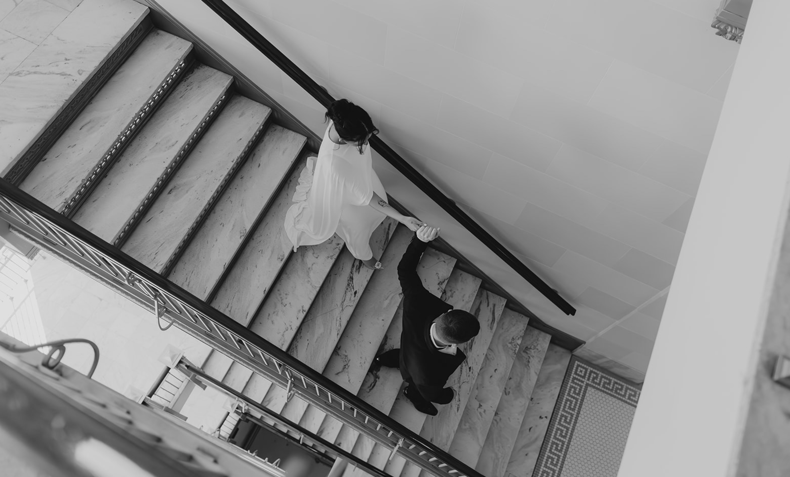 classy engagement couple holding hands on elegant stairs during engagements